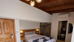 A bedroom with a wooden ceiling, a bed with white linens, a stone wall, and a wooden floor. - Yelken Hotel Akyaka (Ula)