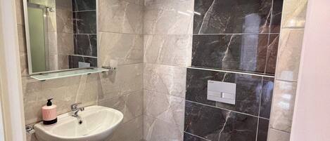 Un baño moderno con un lavamanos blanco, un espejo y un inodoro.