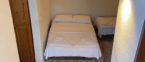 Un dormitorio con una cama, una mesita de noche y una lámpara fijada a la pared.