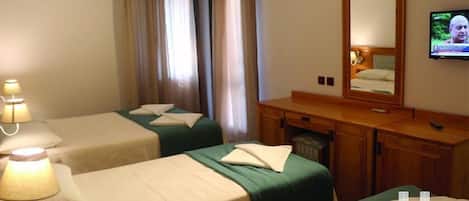 Habitación de hotel con dos camas, un aparador de madera, un televisor y una ventana con cortinas.