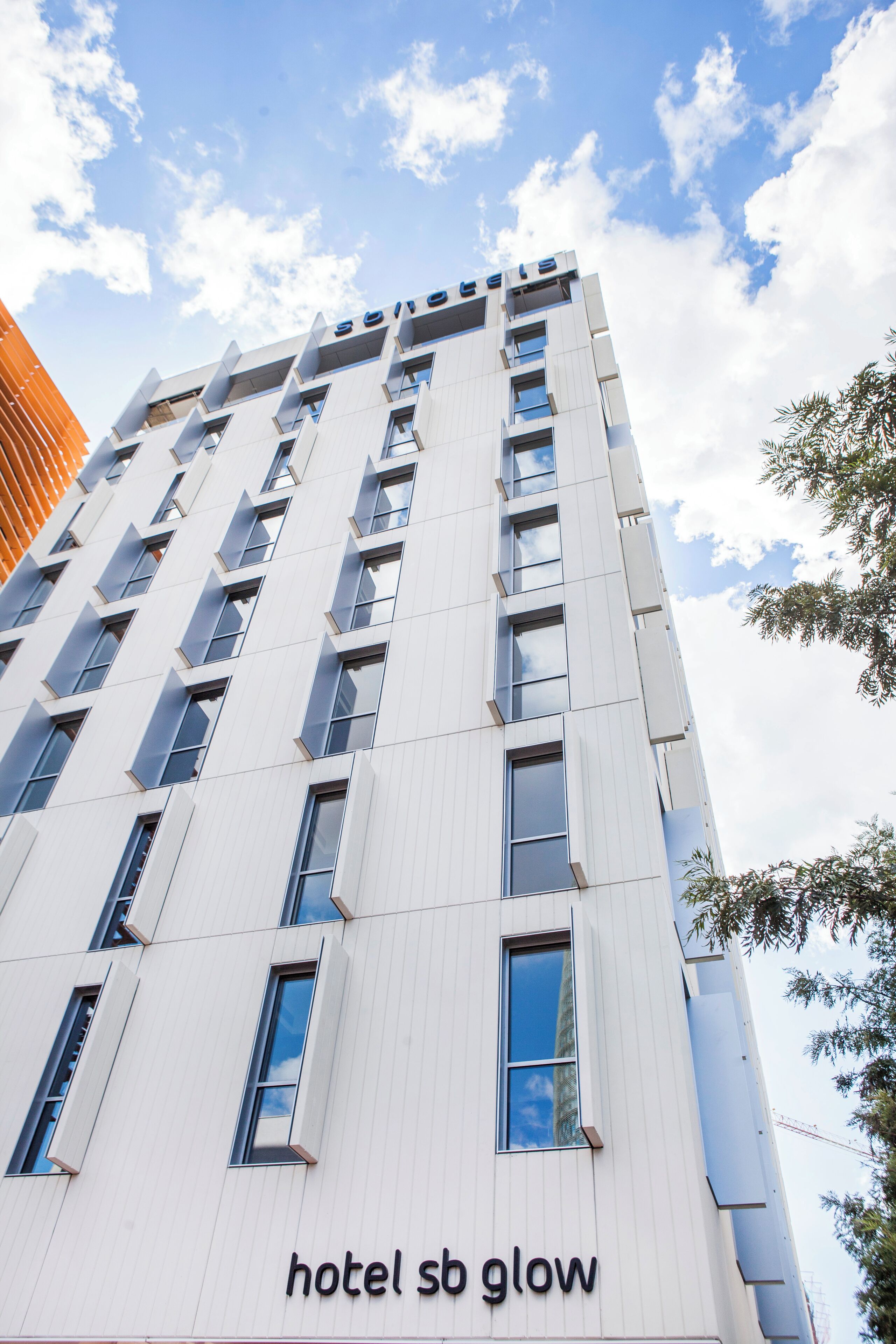 Un moderno edificio de hotel con cielo despejado y un letrero que dice 'hotel sb glow'.