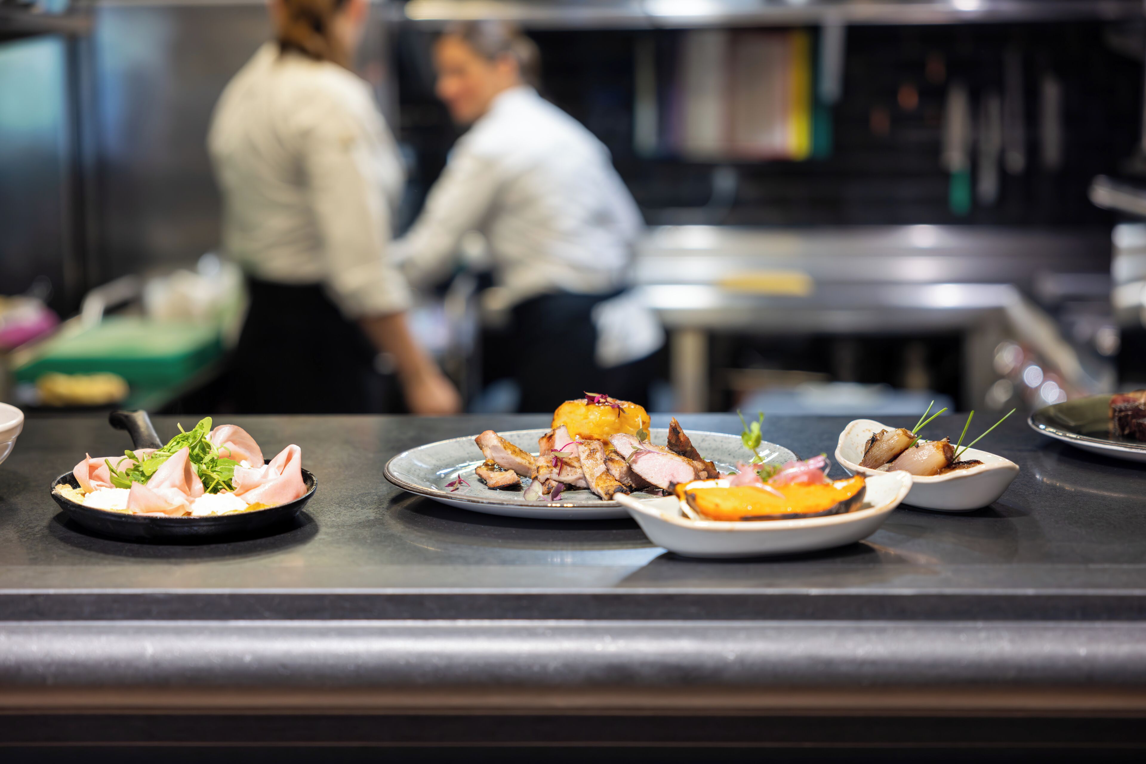 A restaurant counter with various dishes, including a plate with sliced meat and vegetables.