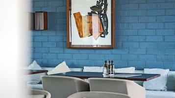 Un ristorante moderno con pareti in mattoni, travi in legno a vista e un quadro astratto incorniciato.