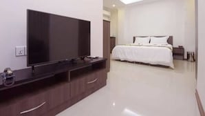 Un dormitorio moderno con una televisión de pantalla plana, una cama con ropa blanca y un diseño minimalista.
