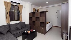 Una sala de estar moderna con un sofá gris, una mesa de centro negra y un mueble de entretenimiento de madera.