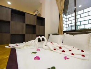 A hotel room with a neatly made bed, a large window with a view, and a wooden wall unit.
