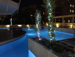 Een buitenzwembad, ligstoelen bij het zwembad