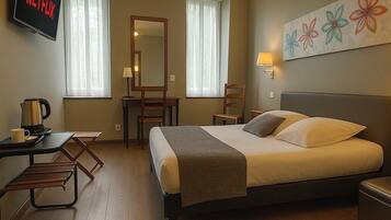 Ein Hotelzimmer mit Bett, Nachttisch, Schreibtisch, Stuhl, Fernseher und einem Bild an der Wand.