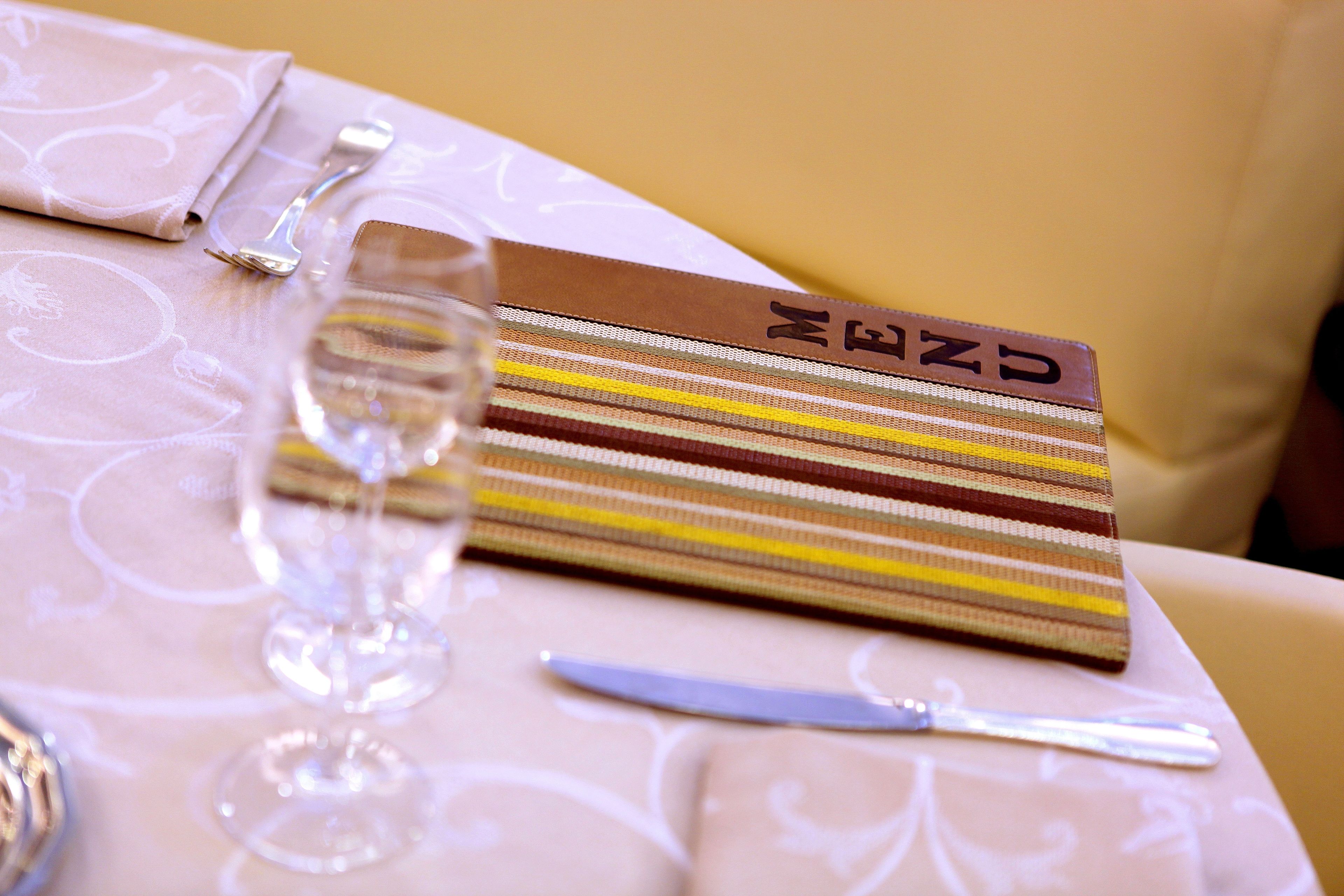 Una mesa bien dispuesta con un mantel a rayas, una copa de vino y cubiertos.