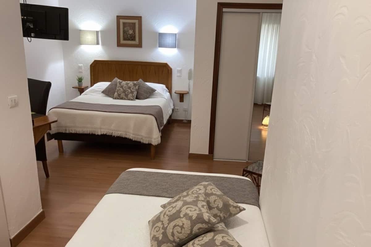 A hotel room with a bed, bedside tables, a TV, and a wall-mounted light.