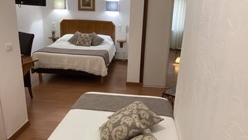A hotel room with a bed, bedside tables, a TV, and a wall-mounted light.