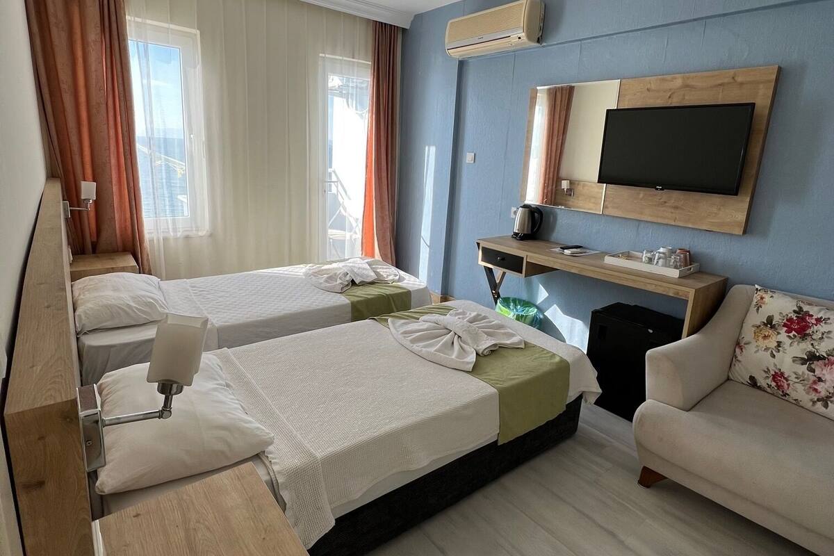 Une chambre d’hôtel avec deux lits, un canapé, une télévision et une petite table avec une bouilloire.