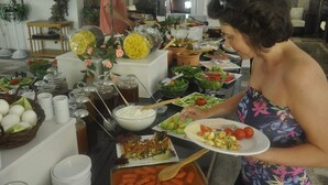 Una mesa de buffet con diferentes alimentos y una persona servándose.