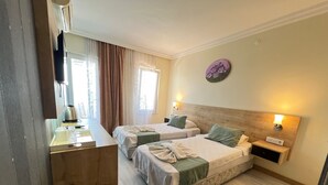 Habitación de hotel con dos camas, un escritorio de madera, una cafetera y una lámpara fijada a la pared.