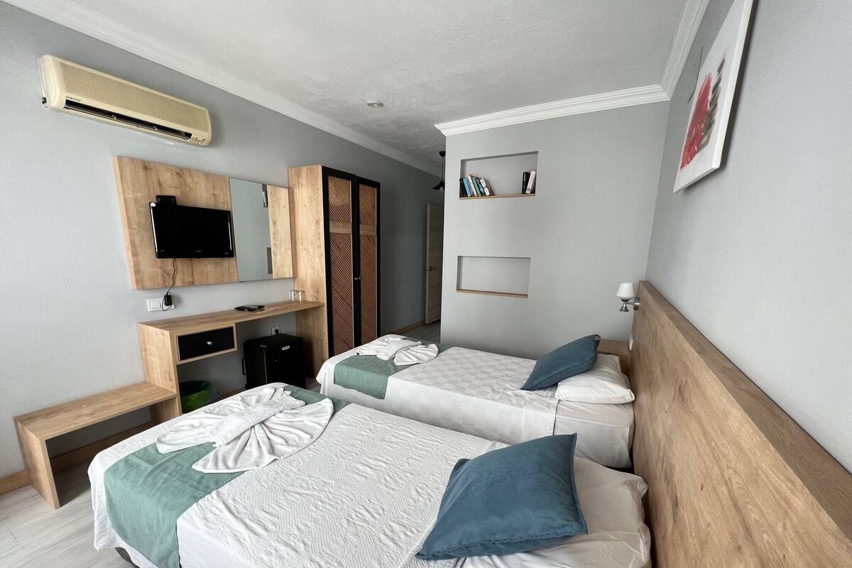 Une chambre d’hôtel avec deux lits, une télévision, un bureau et une armoire.