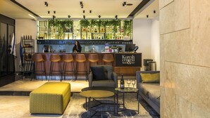 Zona de bar con mostrador, taburetes, sofá y una mesa de centro.