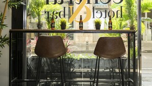 Un restaurante con un escaparate de vidrio, dos sillas marrones, una mesa con un tazón de fruta y plantas en macetas.