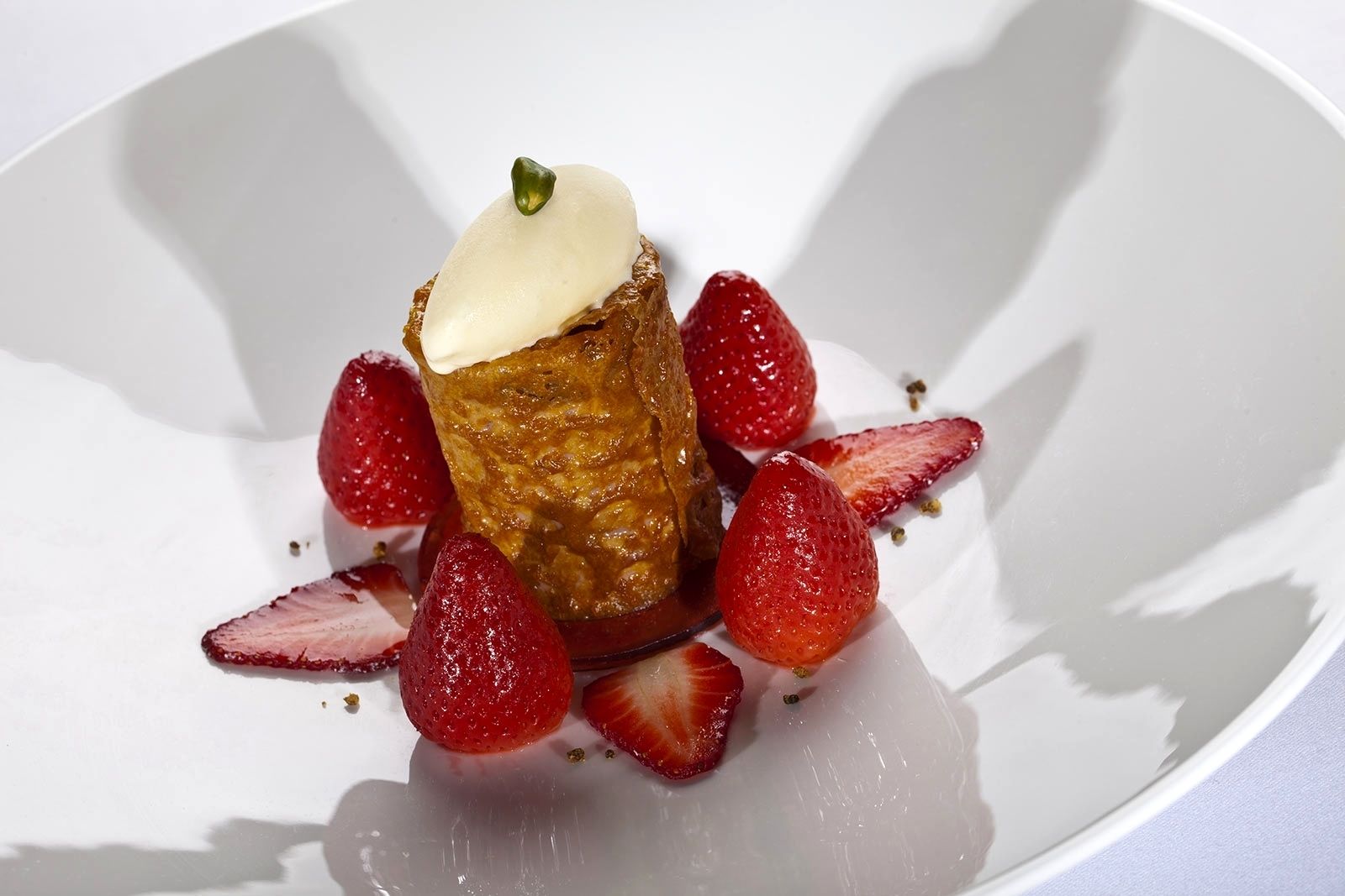 A dessert with a creamy topping and strawberries on a white plate.
