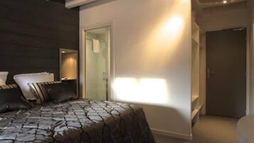 A modern hotel room with a large bed, a walk-in closet, and a bathroom.