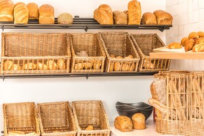 Eine Backwarenauslage mit verschiedenen Brotsorten und Gebäck auf Regalen und in Korbwannen.