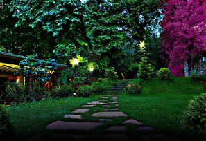 A garden pathway with stepping stones, surrounded by lush greenery and trees.