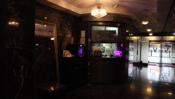 A modern lobby with marble walls, a reception desk, and a chandelier.