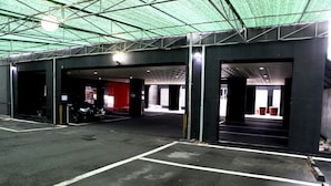 An indoor parking area with multiple open garage doors, a motorcycle, and a red exit sign. - V Hotel (Busan)