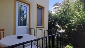 A balcony with a white table and chair, a door, and a window. - Sarihan Apart Otel (Fethiye)