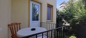 Un balcón con una mesa y una silla blancos, una puerta y una ventana.