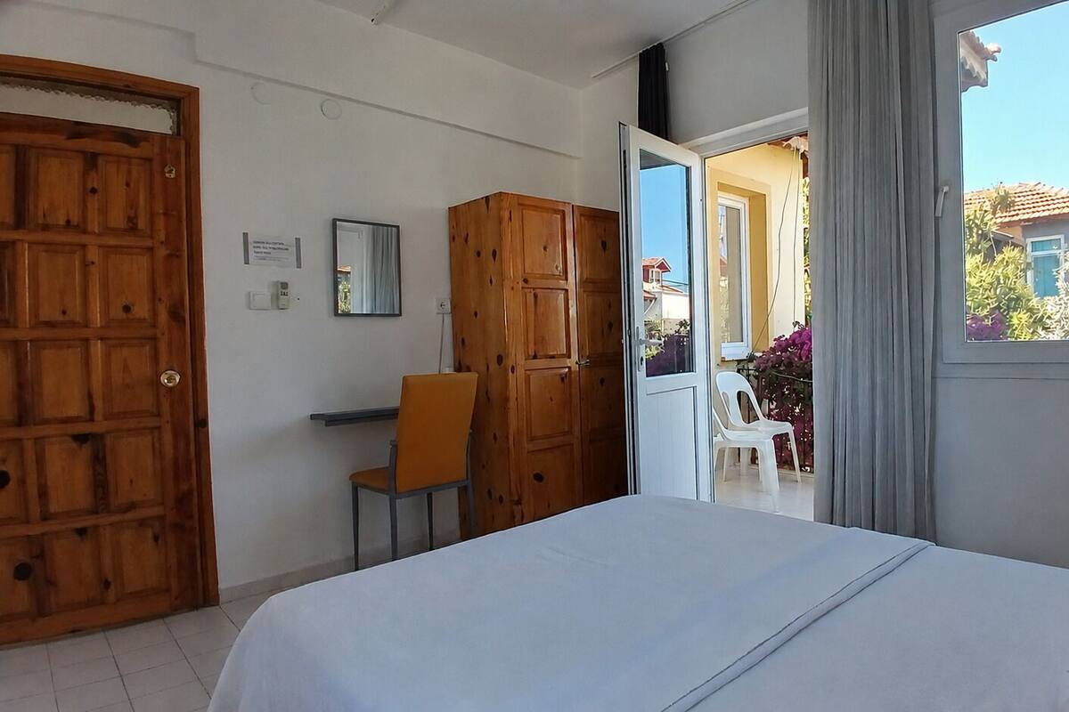 A bedroom with a bed, wooden wardrobe, and a desk with a chair.