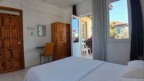 Quarto com cama, guarda-roupa de madeira e escrivaninha com cadeira.