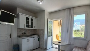 A compact kitchen with a dining area, a sofa, and a window with a view. - Sarihan Apart Otel (Fethiye)