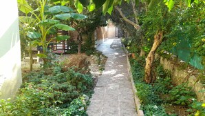 A narrow stone pathway flanked by lush greenery and a wooden fence. - Sarihan Apart Otel (Fethiye)