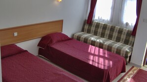 A room with two single beds, a sofa, a wall-mounted light, and a window with curtains. - Hotel Nazar Garden (Fethiye)