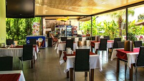 A restaurant with outdoor seating, a bar area, and a television screen mounted on the wall. - Hotel Nazar Garden (Fethiye)