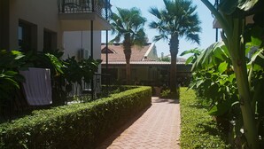 A pathway leading to a building with a balcony, surrounded by lush greenery and palm trees. - Hotel Nazar Garden (Fethiye)