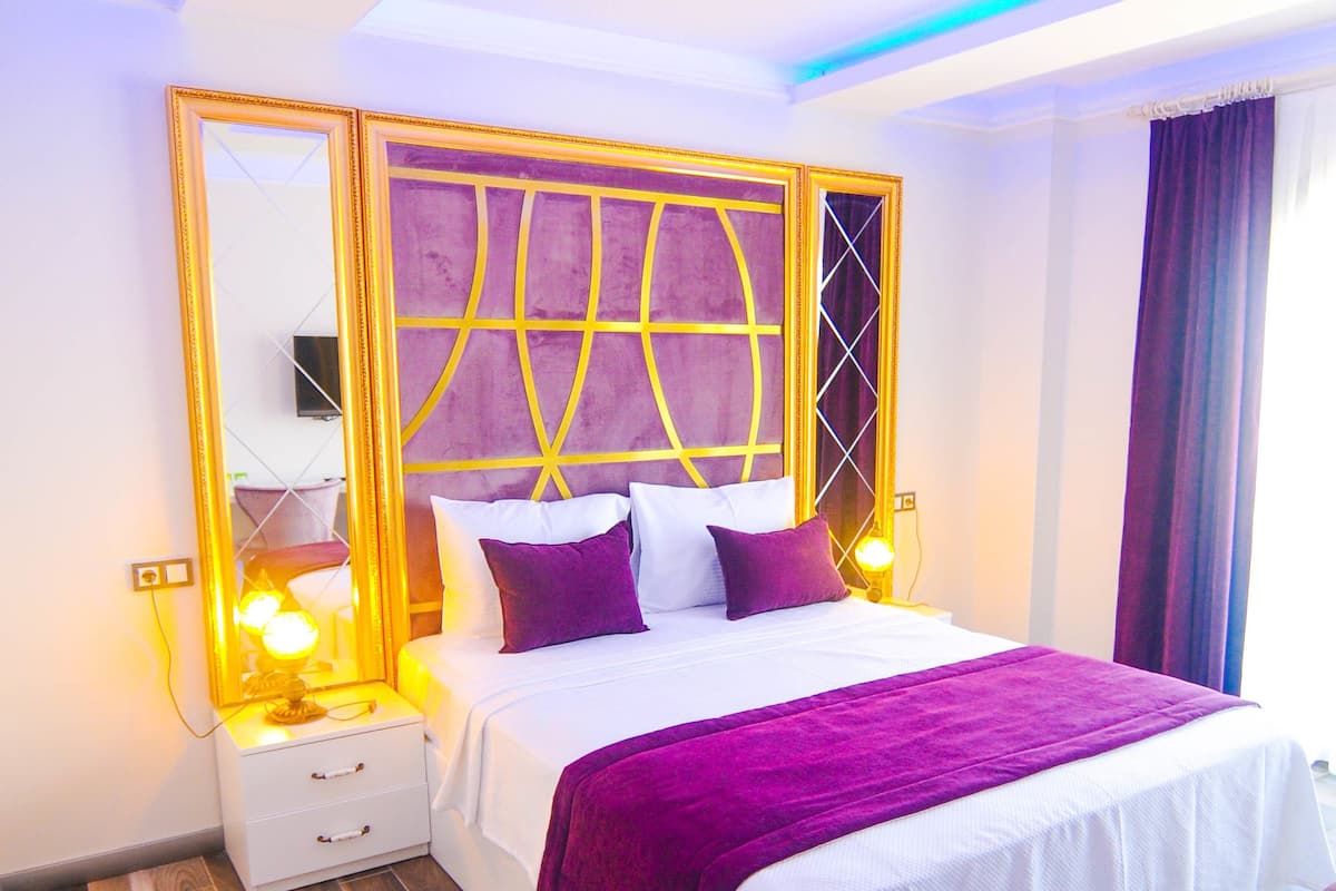 Une chambre d’hôtel moderne avec un grand lit, une table de chevet, une commode et un grand miroir.