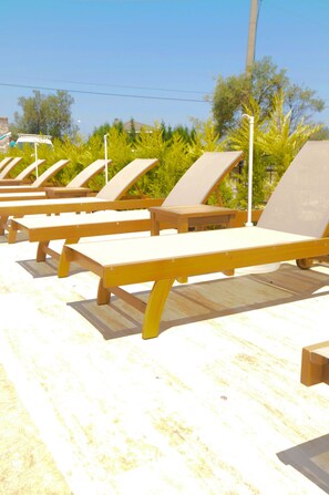 Una piscina al aire libre, sombrillas, sillones reclinables de piscina