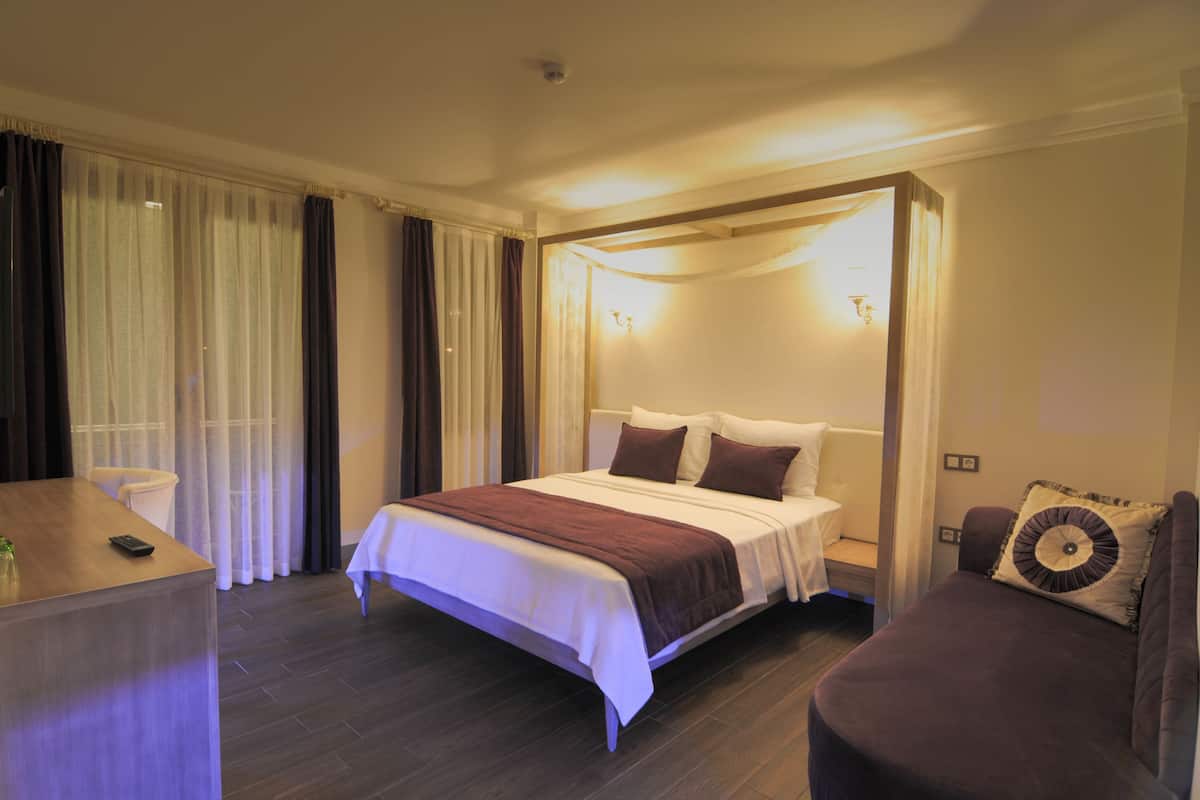Une chambre d’hôtel avec un grand lit, des tables de chevet, un bureau et un canapé.