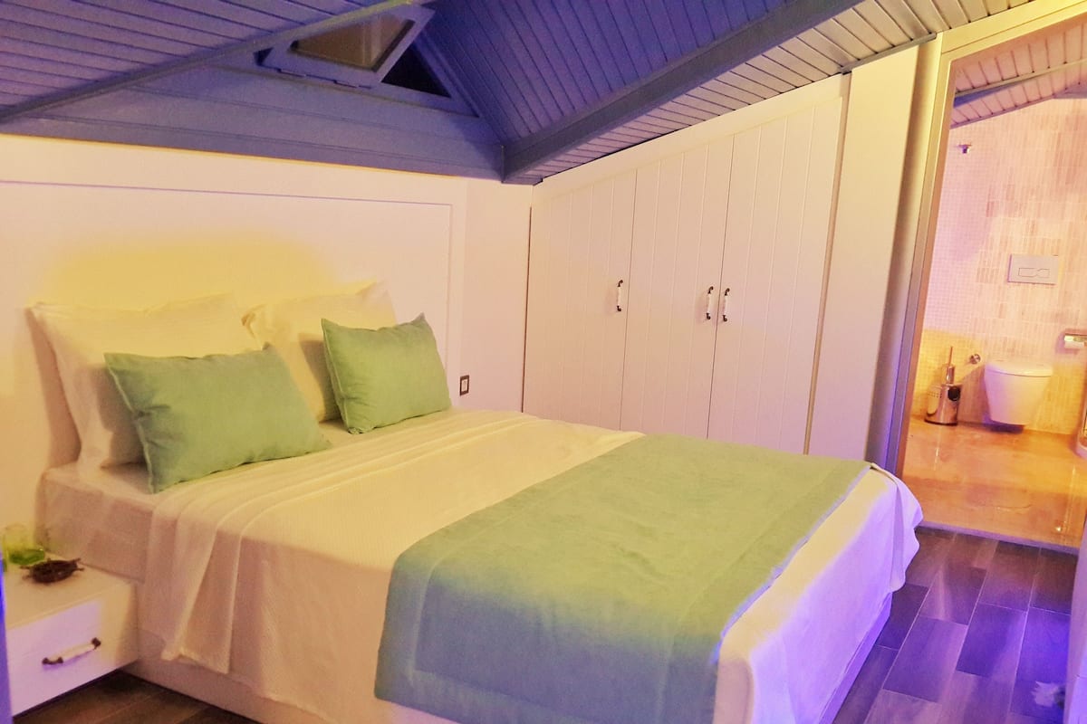Une chambre à coucher avec un lit, des oreillers verts, une table de chevet et une armoire.