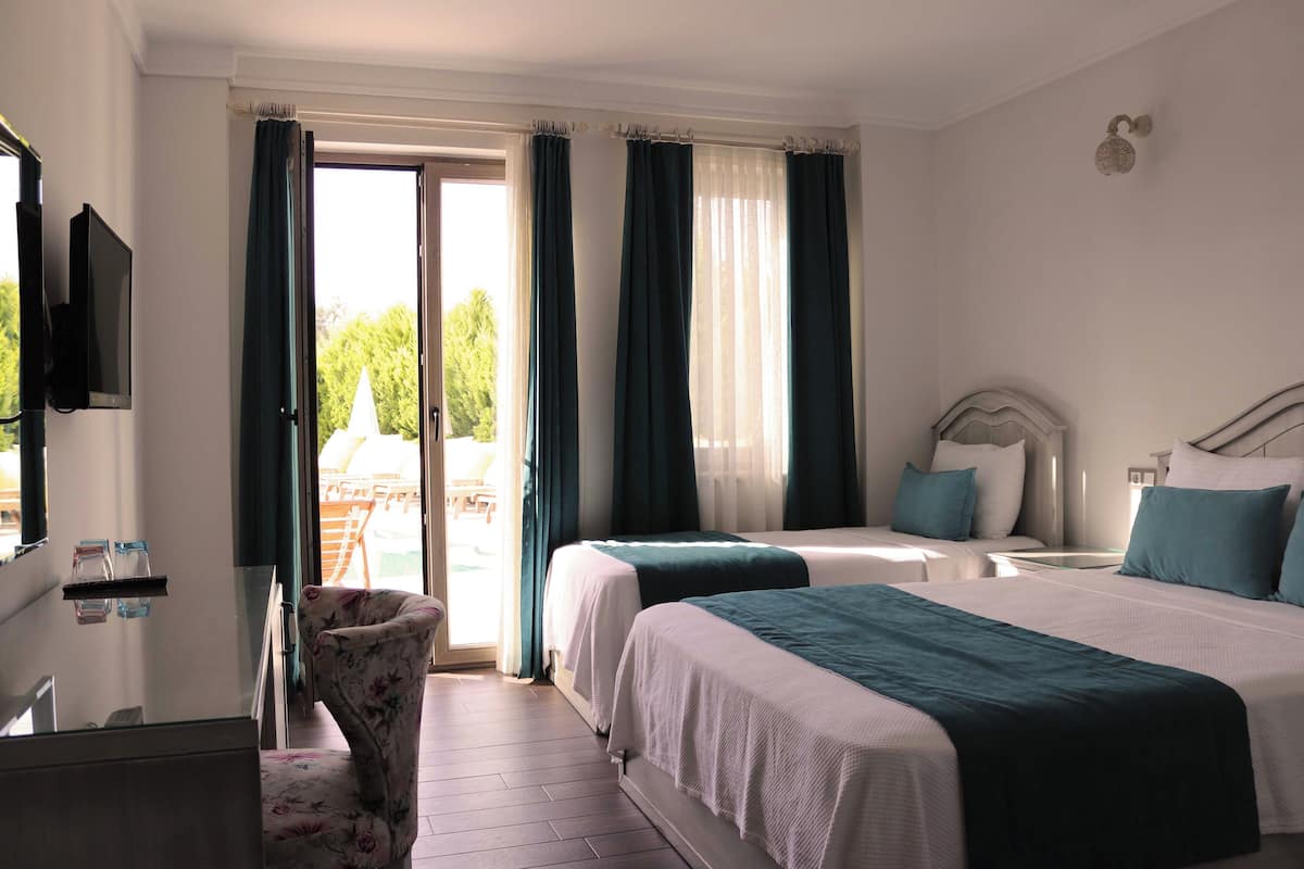 Une chambre d’hôtel avec deux lits, une télévision, une chaise et une vue sur l’extérieur.