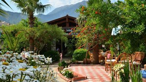 A garden with a checkered patio, outdoor seating, and a mountain backdrop. - Milkyway Apart & Hotels (Fethiye)