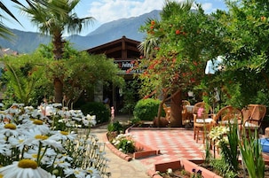 Un jardín con patio a cuadros, mobiliario exterior y montañas al fondo.