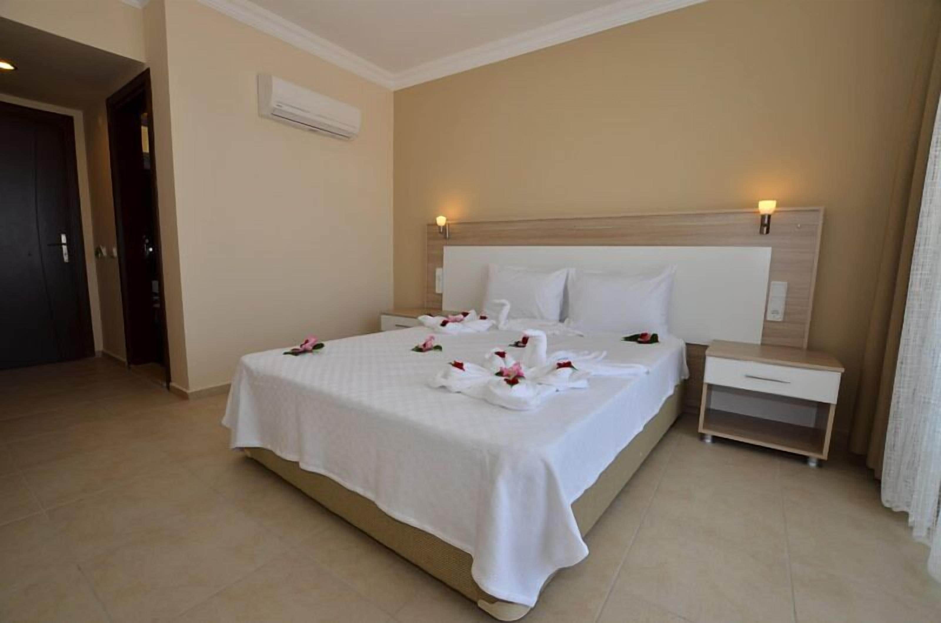 Habitación de hotel con una cama grande, una mesita de noche y un aire acondicionado de pared.