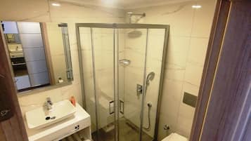 A modern bathroom with a glass-enclosed shower, a white sink, and a toilet.