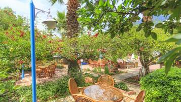 An outdoor patio with wicker furniture, a street lamp, and lush greenery.