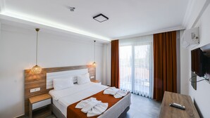 A modern hotel room with a large bed, a wooden nightstand, a desk, and a TV mounted on the wall. - Milkyway Apart & Hotels (Fethiye)