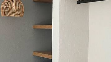 Een modern interieur met houten planken, een geweven hanglamp en een wanddecoratie.