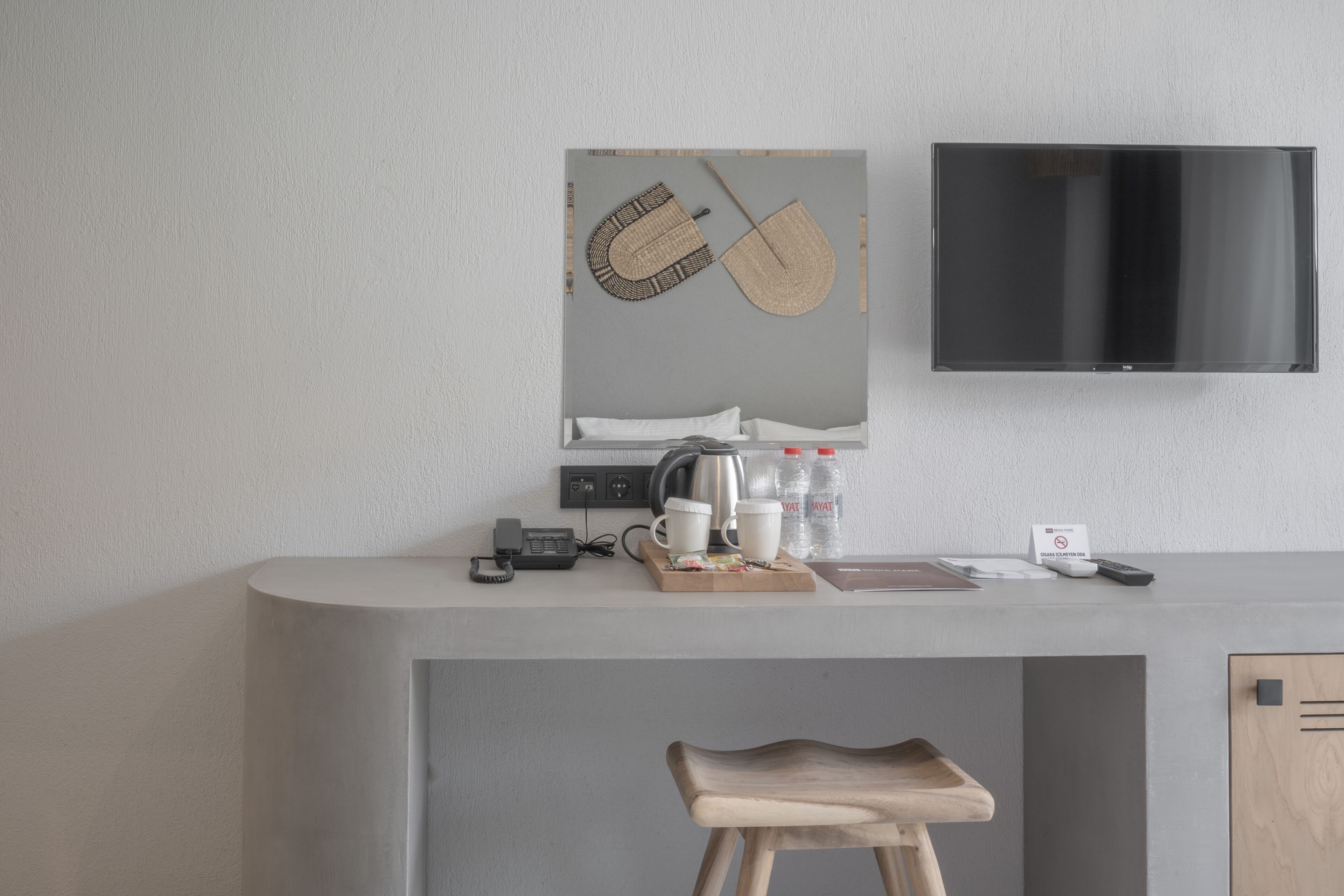 Una cocina moderna con televisión integrada, cafetera y un taburete de madera.