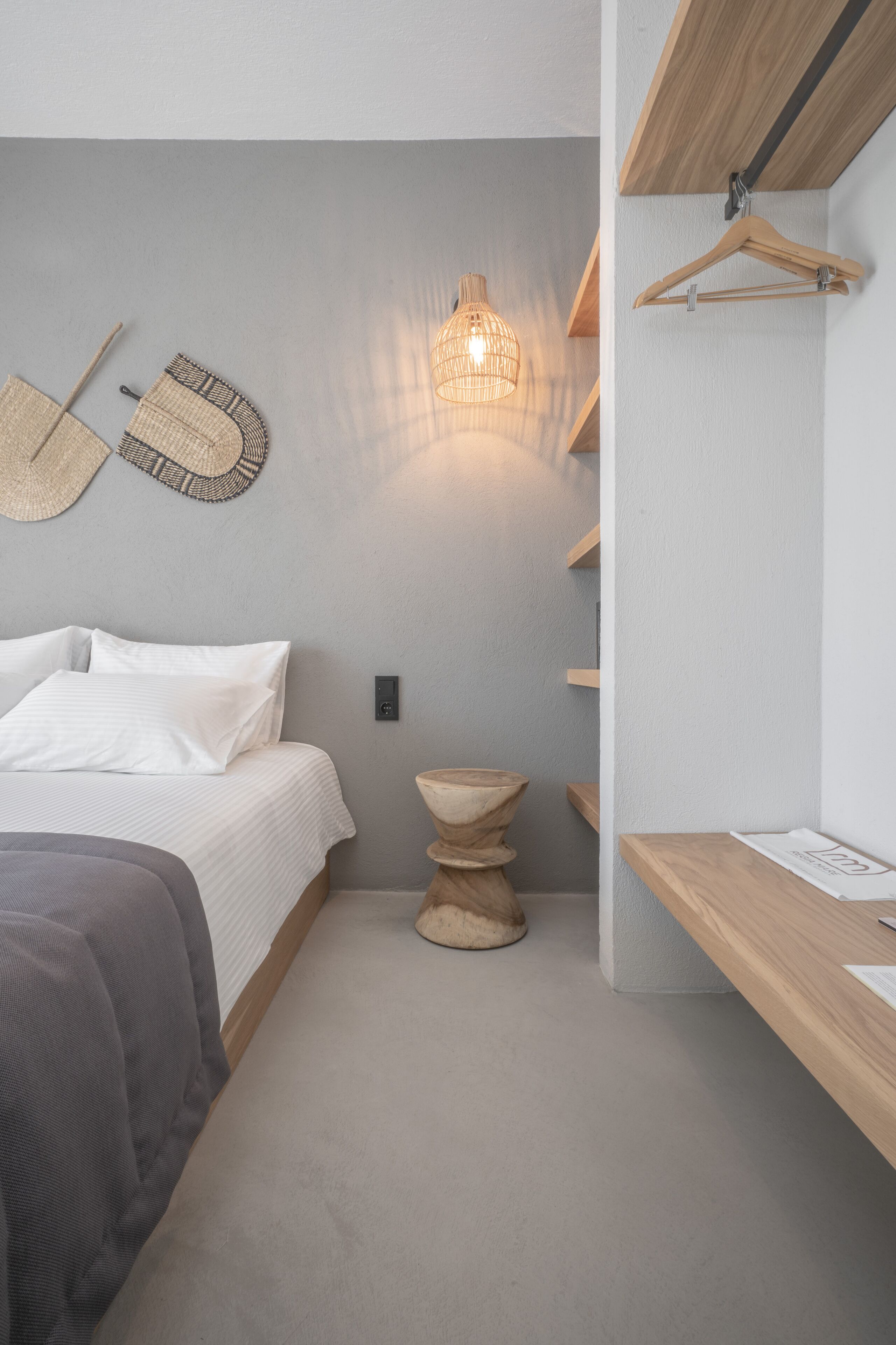 Un dormitorio moderno con cama, mesita de noche, perchero en la pared y lámpara colgante.